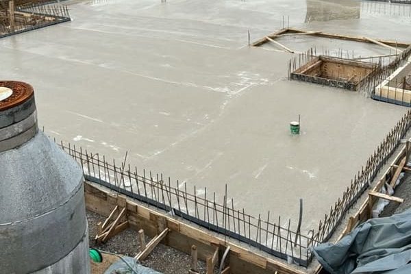 Baugrundstück mit frischem Beton und eisernen Bewehrungen in der Bauphase.