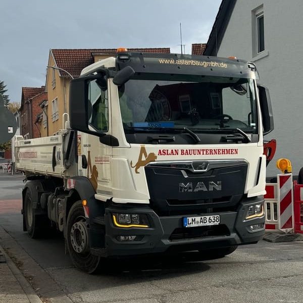 Lkw von MAN mit Bau-Logo, steht an einer Baustelle in einer Wohnstraße.